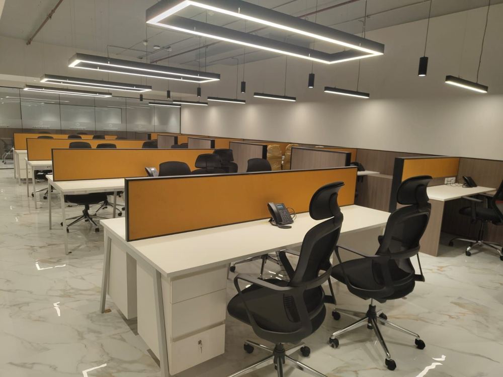 Open-plan workstations with ochre desk screens under linear pendant lights