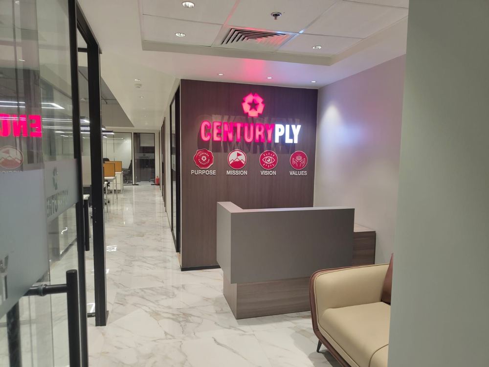 Reception with the illuminated Century Ply sign and a leather lounge chair